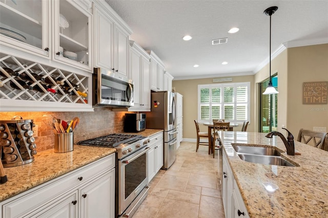 kitchen featuring appliances with stainless steel finishes, decorative light fixtures, white cabinets, and sink