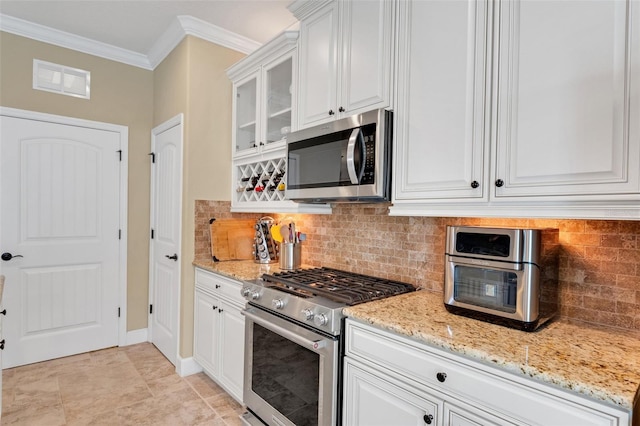 kitchen featuring crown molding, light stone countertops, white cabinets, appliances with stainless steel finishes, and tasteful backsplash