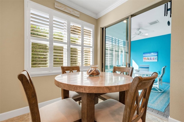 tiled dining space with ceiling fan, crown molding, and a wealth of natural light