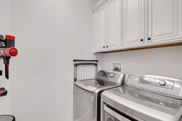 clothes washing area with cabinets and washer and dryer