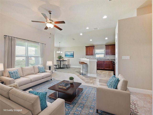 living room with a wealth of natural light and ceiling fan with notable chandelier