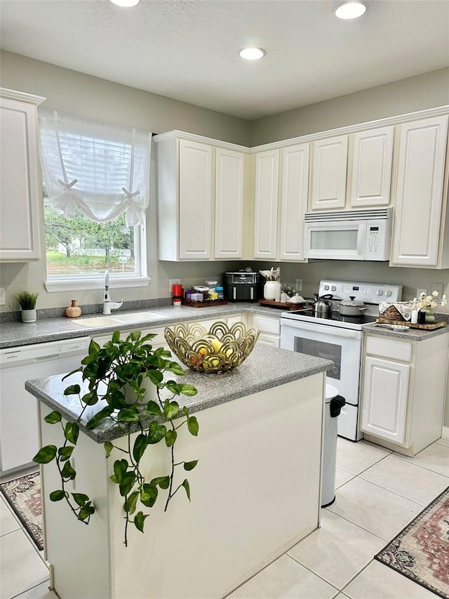 kitchen with white cabinets, a center island, light tile patterned floors, and white appliances