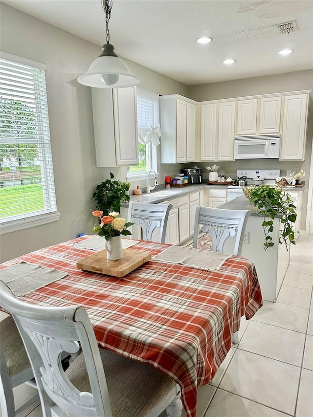 kitchen with sink, light tile patterned flooring, decorative light fixtures, white cabinets, and white appliances