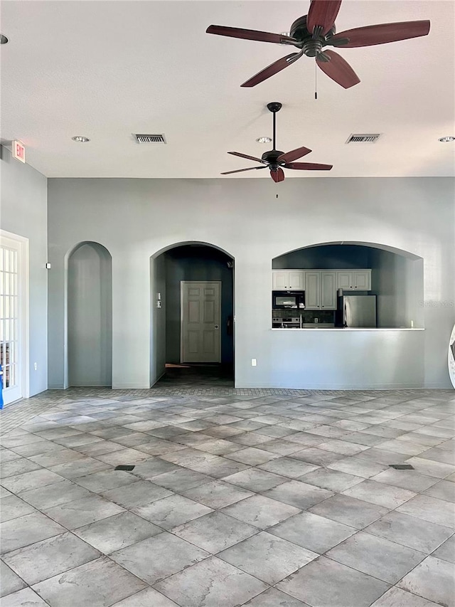 empty room featuring ceiling fan and a high ceiling