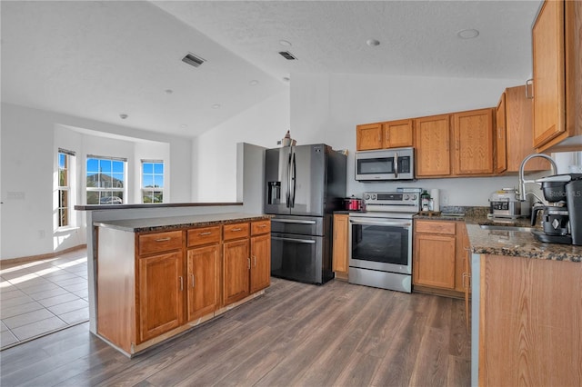 kitchen with dark wood-type flooring, a textured ceiling, appliances with stainless steel finishes, and sink