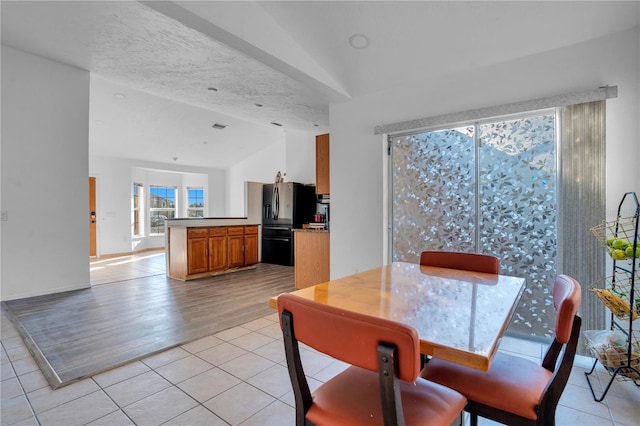 dining area with light hardwood / wood-style flooring, a textured ceiling, and lofted ceiling