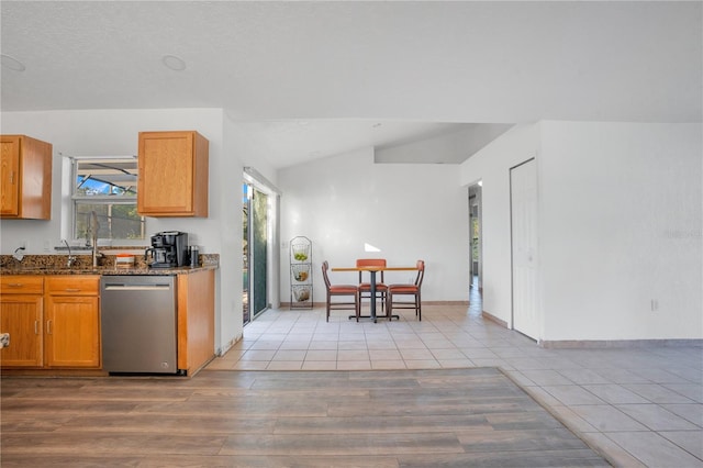 kitchen featuring light hardwood / wood-style flooring, lofted ceiling, dishwasher, and dark stone counters