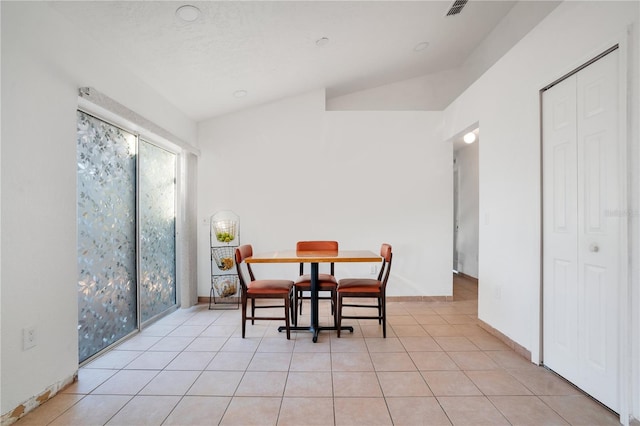 dining room featuring lofted ceiling and light tile patterned flooring