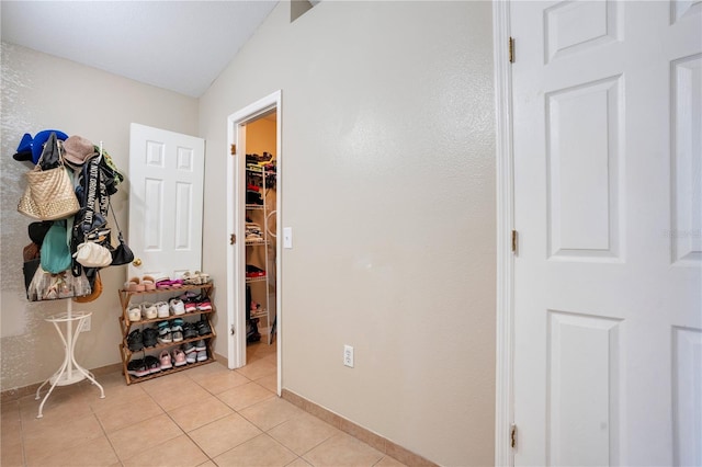 hallway with lofted ceiling and light tile patterned floors