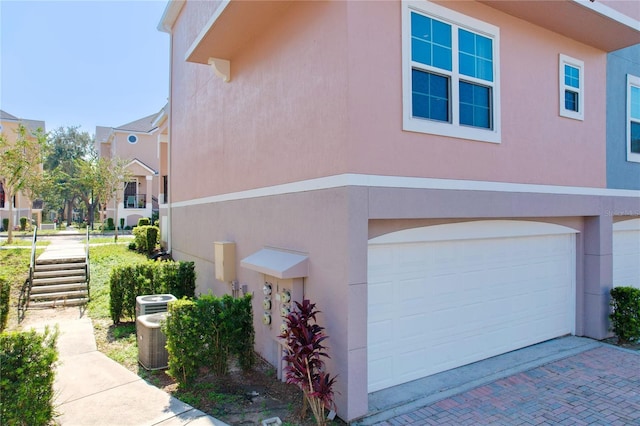 view of property exterior featuring central AC unit and a garage