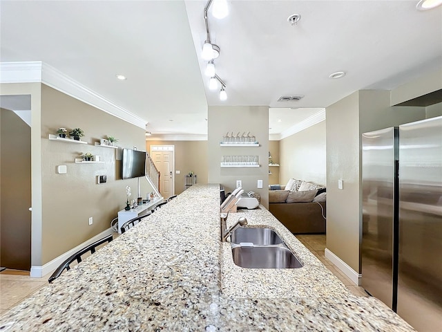 kitchen featuring crown molding, sink, stainless steel fridge, light stone countertops, and light tile patterned flooring