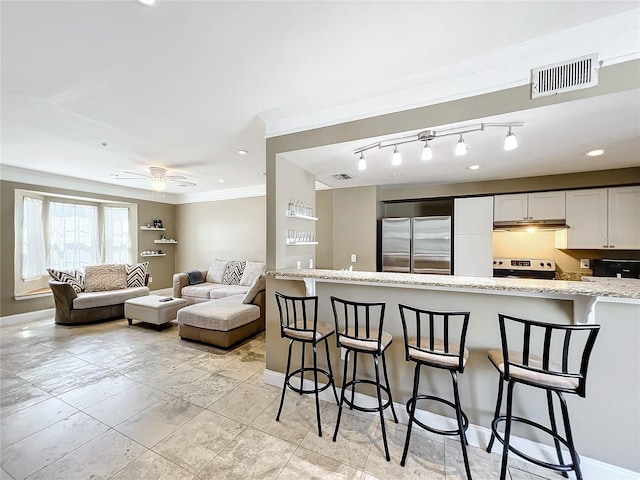 kitchen with stainless steel refrigerator, white cabinetry, light stone countertops, white electric stove, and a breakfast bar