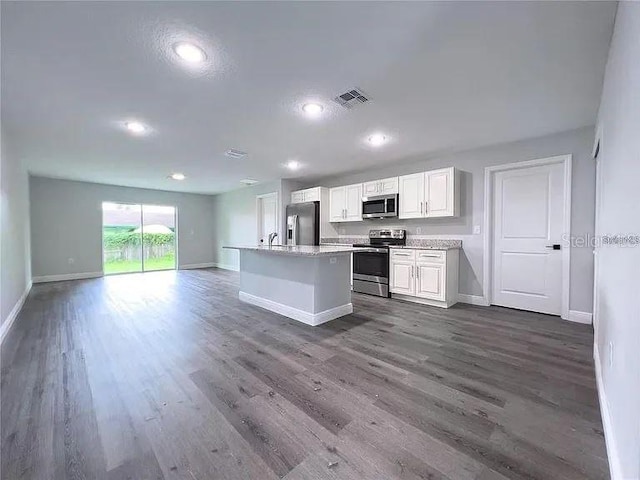 kitchen with light stone counters, a center island, dark hardwood / wood-style floors, white cabinets, and appliances with stainless steel finishes