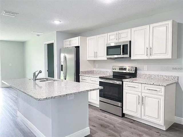 kitchen featuring white cabinets, sink, a textured ceiling, appliances with stainless steel finishes, and light wood-type flooring