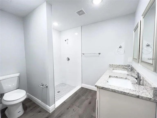 bathroom featuring vanity, a shower, hardwood / wood-style floors, and toilet