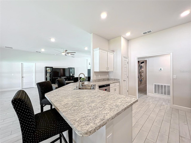 kitchen featuring dishwasher, kitchen peninsula, sink, a breakfast bar, and white cabinets