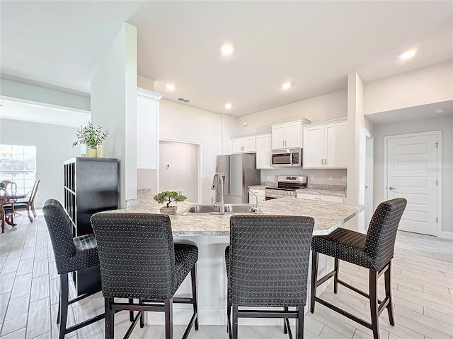 kitchen with stainless steel appliances, a breakfast bar area, kitchen peninsula, and white cabinets