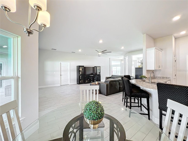 dining area featuring light hardwood / wood-style floors, sink, and ceiling fan with notable chandelier