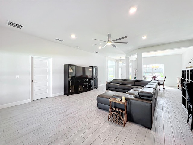 living room featuring ceiling fan with notable chandelier and light hardwood / wood-style floors