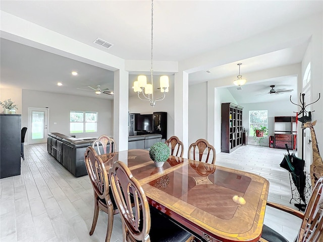 dining space featuring light hardwood / wood-style floors, lofted ceiling, and ceiling fan with notable chandelier