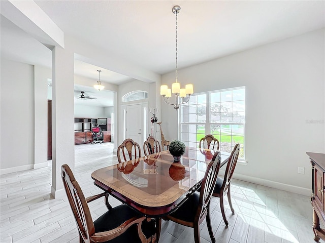 dining area featuring light hardwood / wood-style flooring and ceiling fan with notable chandelier