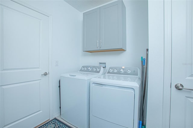 laundry room featuring a textured ceiling, cabinets, and washer and clothes dryer