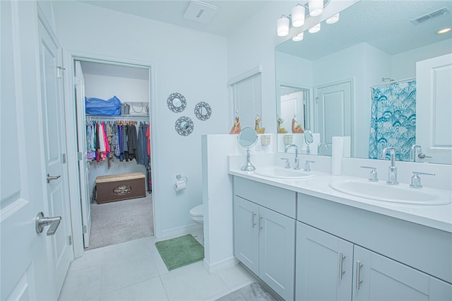 bathroom featuring walk in shower, vanity, toilet, and tile patterned floors