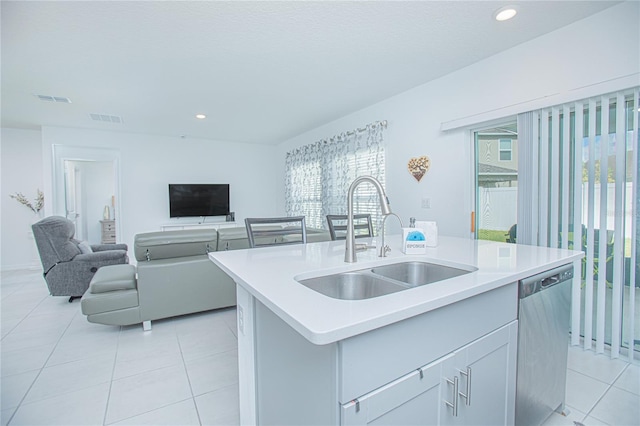 kitchen with stainless steel dishwasher, sink, a center island with sink, and light tile patterned floors