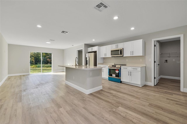 kitchen featuring a center island with sink, white cabinetry, stainless steel appliances, and light wood-type flooring