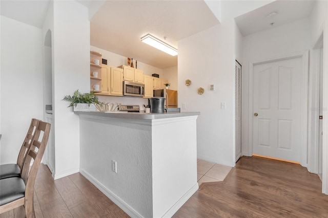 kitchen with stainless steel appliances, kitchen peninsula, and hardwood / wood-style flooring