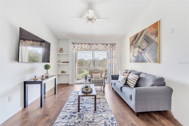 living room with lofted ceiling, dark hardwood / wood-style flooring, ceiling fan, and built in shelves