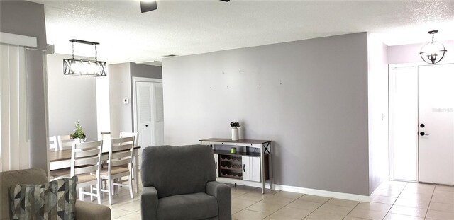 sitting room with ceiling fan, a textured ceiling, and light tile patterned flooring