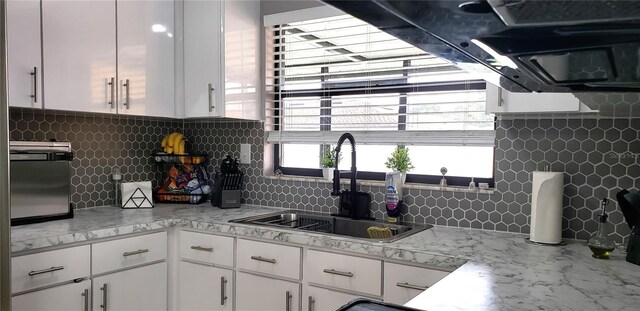 kitchen featuring white cabinetry, light stone counters, tasteful backsplash, and sink