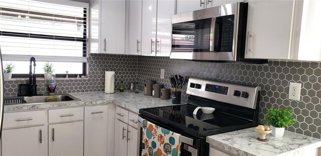 kitchen with sink, decorative backsplash, white cabinetry, and stainless steel appliances