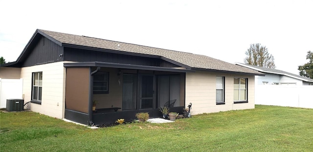 back of house with cooling unit, a sunroom, and a lawn