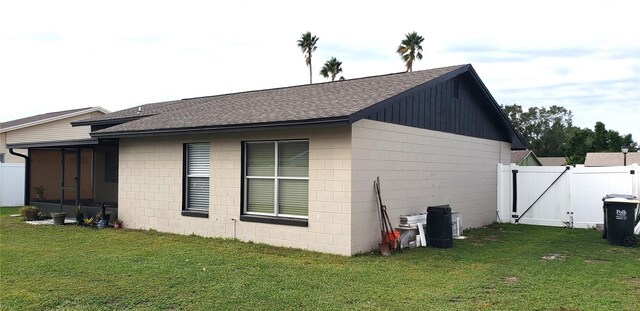 view of side of home featuring a sunroom and a lawn