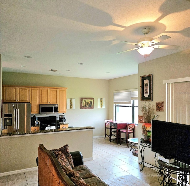 kitchen featuring kitchen peninsula, sink, light tile patterned floors, appliances with stainless steel finishes, and ceiling fan