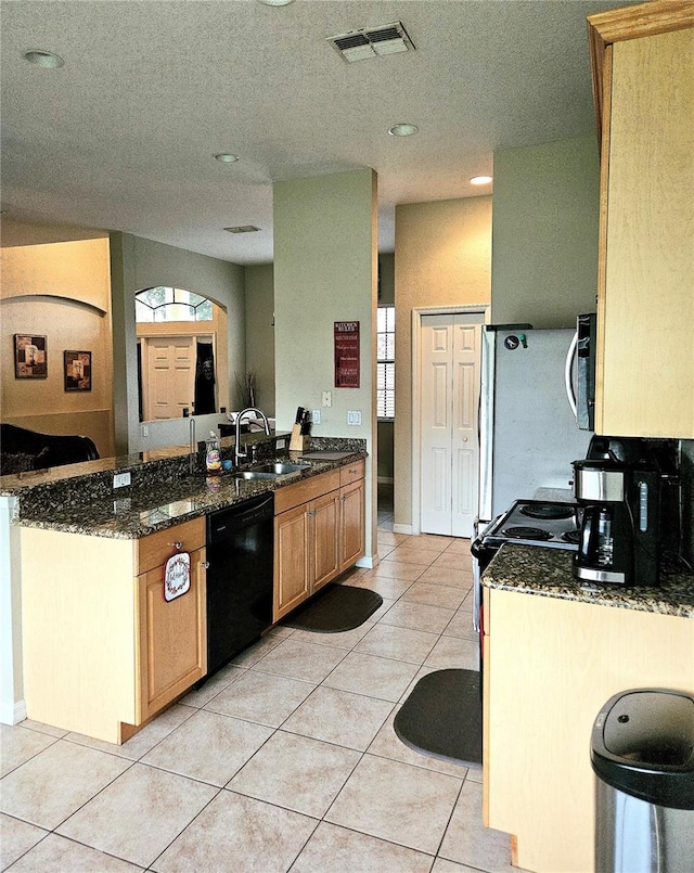 kitchen featuring kitchen peninsula, dark stone counters, light tile patterned flooring, sink, and stainless steel appliances