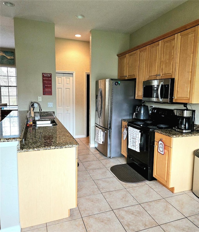 kitchen featuring stainless steel appliances, sink, dark stone counters, and light tile patterned floors