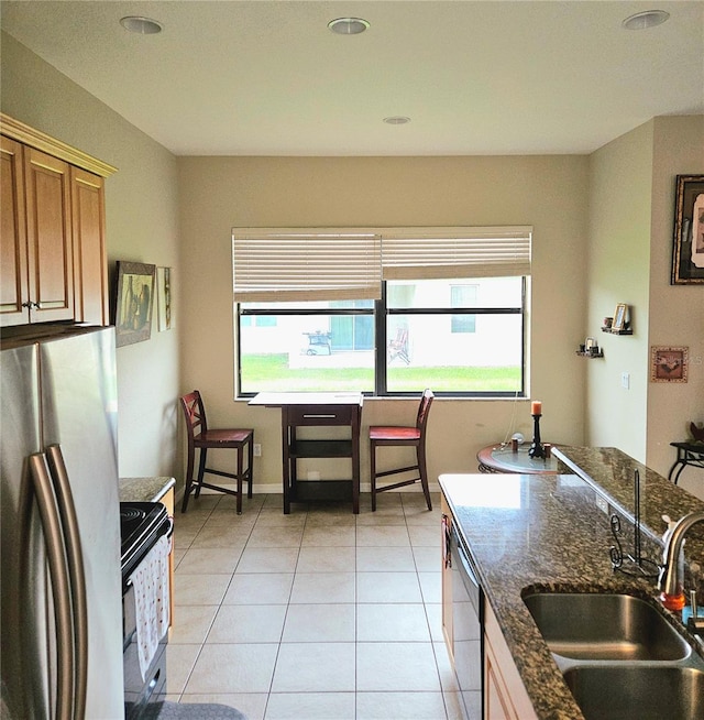 kitchen with sink, appliances with stainless steel finishes, a healthy amount of sunlight, and light tile patterned flooring