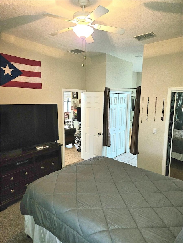 carpeted bedroom featuring ceiling fan and a textured ceiling