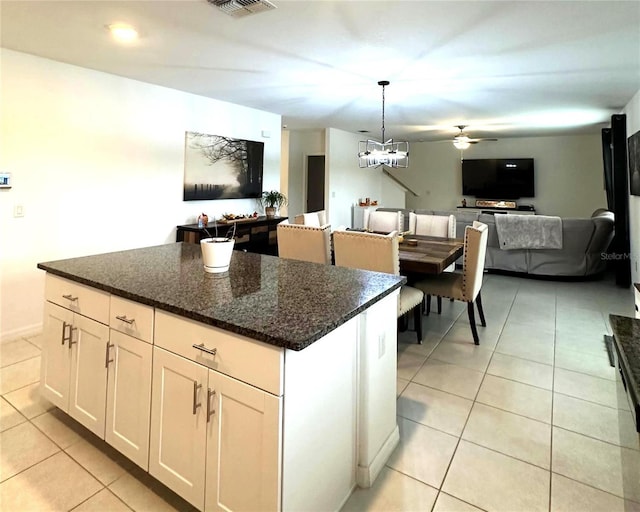 kitchen featuring a center island, dark stone counters, ceiling fan, decorative light fixtures, and white cabinetry