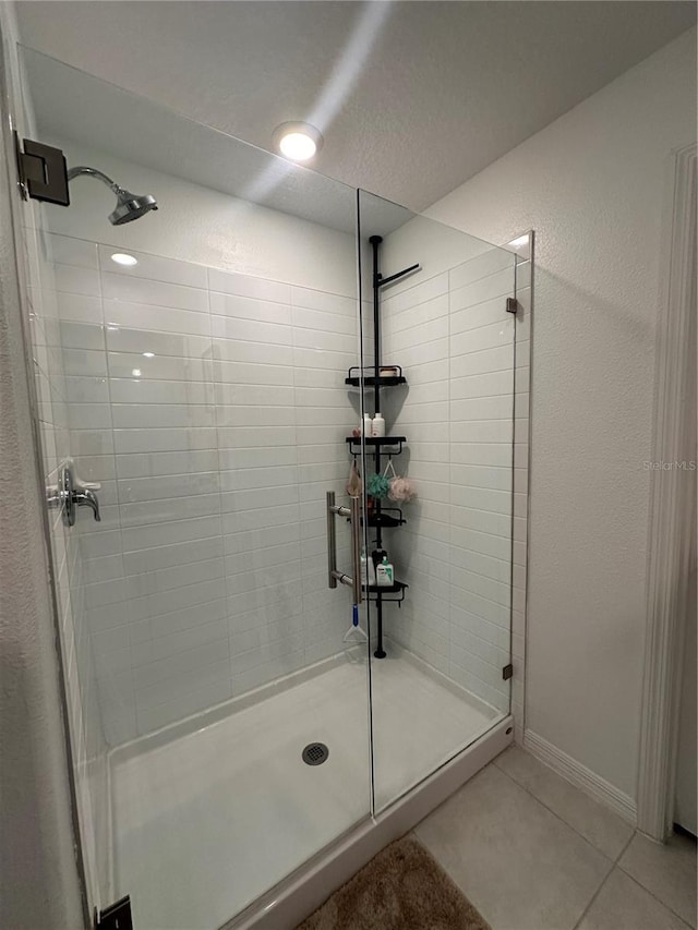 bathroom featuring tile patterned flooring, an enclosed shower, and a textured ceiling