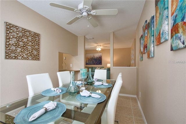 dining area featuring tile patterned floors, a ceiling fan, and baseboards