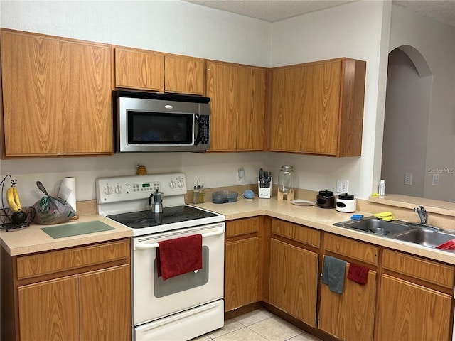 kitchen with sink, light tile patterned flooring, a textured ceiling, and electric stove