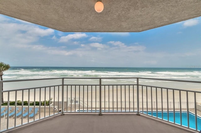 balcony with a water view and a view of the beach