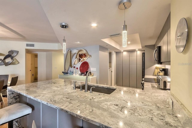 kitchen with a breakfast bar area, kitchen peninsula, sink, and pendant lighting