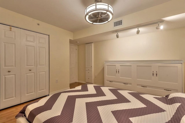 unfurnished bedroom with track lighting, light hardwood / wood-style floors, and a closet