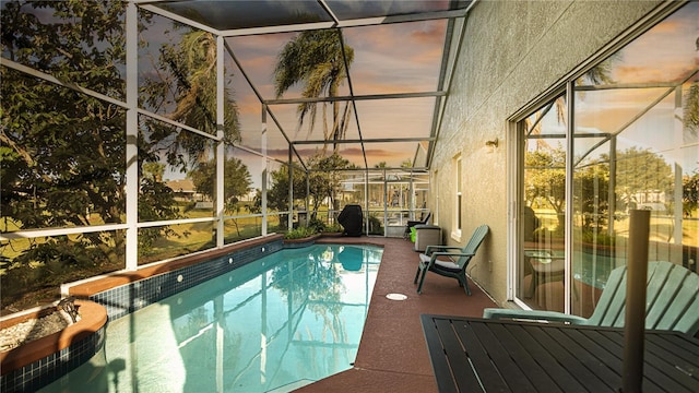 pool at dusk featuring a patio and a lanai