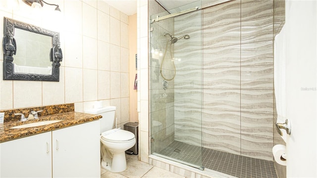 bathroom with an enclosed shower, toilet, tile patterned floors, tile walls, and vanity